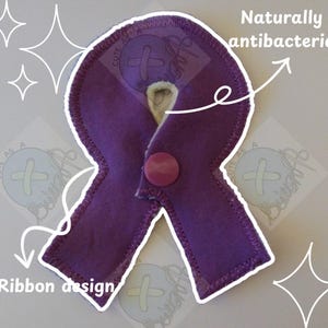 May include: A purple ribbon-shaped item with a button closure. The item has a white border and the text "Naturally antibacterial" is visible. The design is a ribbon shape.
