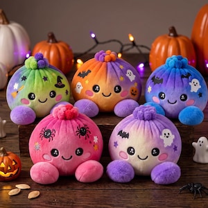 Peut inclure: Cinq peluches rondes avec des visages souriants et des pompons sur le dessus, présentant des couleurs dégradées et des motifs sur le thème d'Halloween comme des fantômes, des chauves-souris, des araignées et des chapeaux de sorcière.