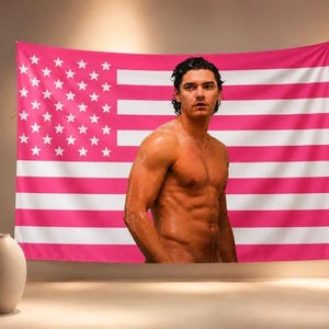 Puede incluir: Un tapiz de pared rectangular que presenta un diseño de bandera estadounidense estilizada con rayas horizontales alternas de color rosa intenso y blanco y un campo de estrellas blancas sobre un fondo rosa intenso, centrado con el retrato de una persona sin camisa.