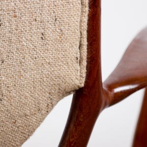 May include: Close-up of a wooden chair arm and backrest. The chair features a light brown, textured fabric and a dark, glossy wooden frame. The design is minimalist and the wood has a curved shape.