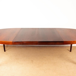 Könnte beinhalten: Ein ovaler Esstisch aus Holz mit dunkelbraunem Finish. Der Tisch hat vier Beine und eine glatte, polierte Oberfläche. Der Tisch ist etwa 183 cm lang und 102 cm breit.