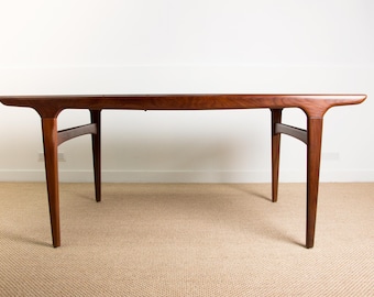 Può includere: Tavolo in legno in stile moderno di metà secolo con finitura marrone scuro. Il tavolo ha un piano rettangolare con bordi curvi e gambe angolate. Il tavolo è lungo circa 152 cm.