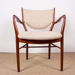 May include: A mid-century modern armchair with a curved back and armrests. The chair features a light beige upholstered seat and backrest, set within a dark wood frame. The chair's design is simple and elegant, with a focus on comfort and style.