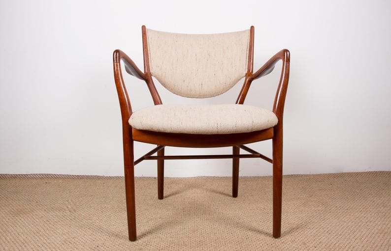 May include: A mid-century modern armchair with a curved back and armrests. The chair features a light beige upholstered seat and backrest, set within a dark wood frame. The chair's design is simple and elegant, with a focus on comfort and style.