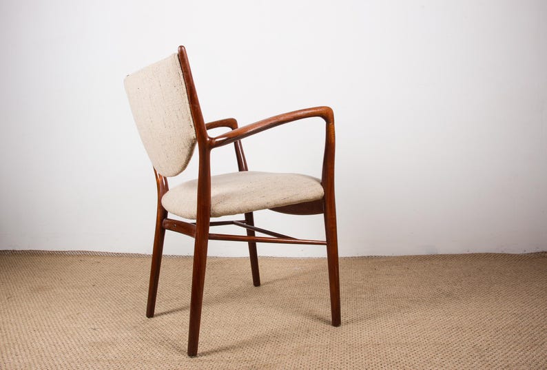 May include: A mid-century modern armchair with a curved back and armrests. The chair features a wooden frame with a warm, reddish-brown finish. The seat and back are upholstered in a light beige fabric.