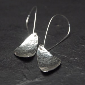 May include: A pair of silver dangle earrings with hammered, teardrop-shaped pendants.