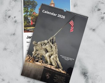 May include: Two spiral-bound calendars. The front calendar features a statue of soldiers raising a flag, with the text "Calendar 2026." The other calendar shows a building and the text "Auburn University Alabama."