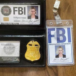 Könnte beinhalten: Ein FBI-Ausweis und ein Abzeichen werden gezeigt. Der Ausweis befindet sich in einem schwarzen Lederhalter, und das Abzeichen ist goldfarben. Ein separater FBI-Ausweis befindet sich in einem transparenten Kunststoffhalter. Die Ausweise zeigen ein Foto einer Person.