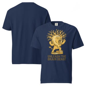 May include: Navy blue t-shirt featuring a golden lion illustration with the text "UNLEASH THE BRAIN BEAST". The lion is roaring and standing on top of two books. The shirt is a short-sleeved crew neck.