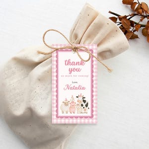 Pink farm thank you tag with watercolor cow, pig, sheep and chicken attached to a gift bag with twine.