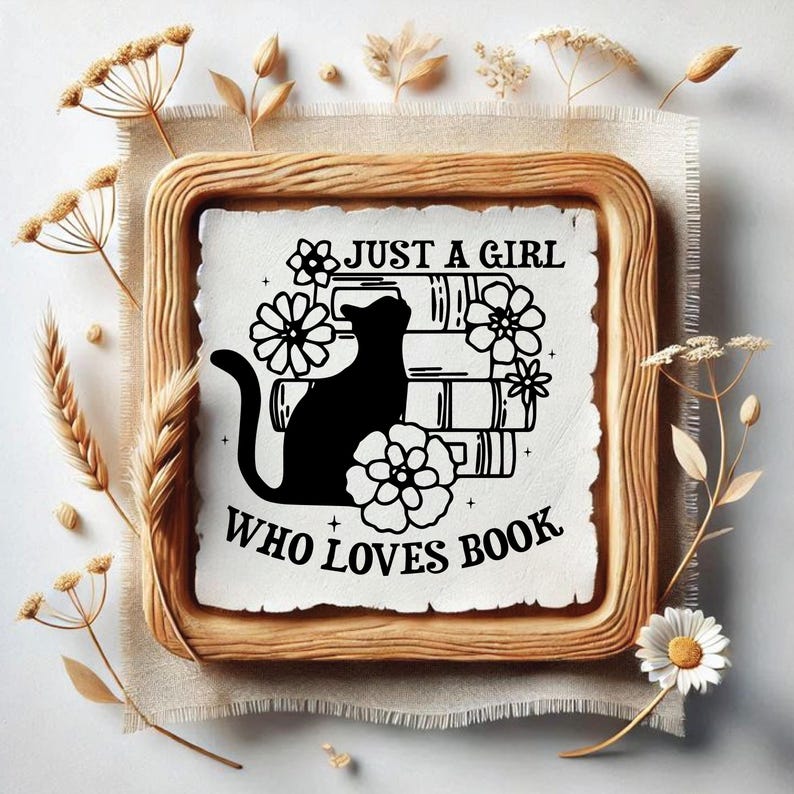May include: A framed print with the text "JUST A GIRL WHO LOVES BOOK" and a black cat silhouette atop a stack of books, surrounded by floral accents. The frame is a light brown color, and the background is a neutral beige.