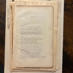 May include: A stack of aged paper ephemera, including a printed page with French text titled "ROLLA." The pages are off-white with visible aging and wear. A partial image of a clock face is visible at the top. The text "HIGH POINT, NORTH CAROLINA" is printed at the bottom.
