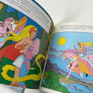 May include: A vintage comic book illustration featuring She-Ra and a pink unicorn with wings. The artwork is colorful, with text bubbles and a vibrant landscape. The text reads, "Thank the Glitterbugs. Without them you'd still be in Catra's dungeon."