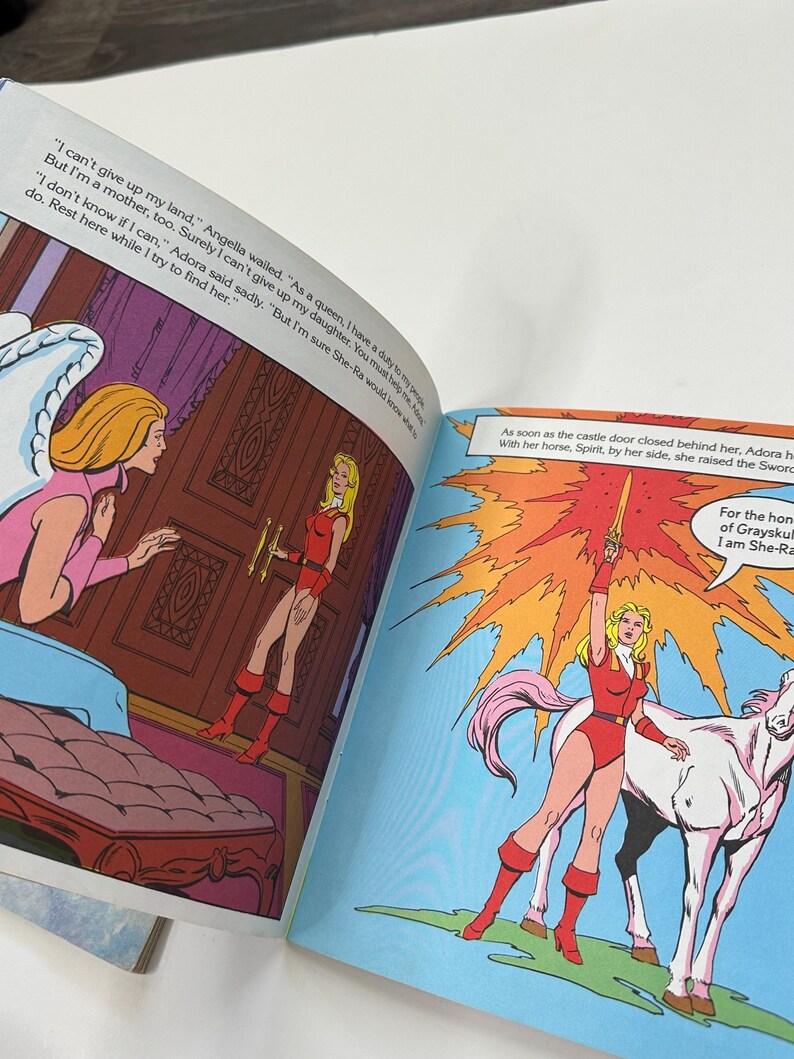 May include: Comic book illustration featuring a blonde woman in a red outfit, holding a sword and standing on a white horse. Text bubbles contain dialogue. The scene is set against a blue background with an orange burst.