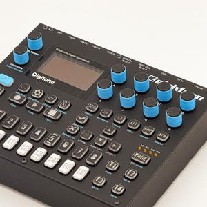 May include: A black Elektron Digitone polyphonic digital synthesizer featuring a central display screen, eight blue rotary knobs, and a grid of numbered buttons. The interface includes various control keys for MIDI, pattern, and sound settings.