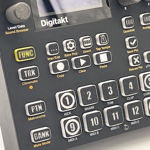 May include: A black Digitakt drum machine and sampler featuring a central screen, numerous square buttons labelled with numbers and functions, and rotary knobs. The interface includes text labels such as Master Volume, Func, Trk, Ptn, Bank, and MIDI A through D.