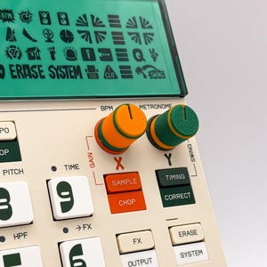 Puede incluir: Un sampler de música electrónica de color beige con una pantalla verde que muestra varios iconos y el texto ERASE SYSTEM. El dispositivo incluye perillas de control texturizadas en naranja y verde etiquetadas como BPM y METRONOME, junto con botones marcados como SAMPLE, CHOP, TIMING, CORRECT, FX, OUTPUT, ERASE y SYSTEM.