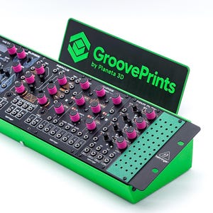 May include: A green modular synthesizer rack housing multiple black Behringer modules with bright pink knobs. A black sign with green text reading GroovePrints by Planeta 3D is attached to the back. The unit features various inputs, outputs, and controls.