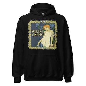 May include: Black hoodie featuring a framed graphic with the text "SOILENT GREEN" and an illustration of a woman in a white dress. The graphic has a gold border with blue flowers and a dark green background.
