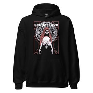 May include: Black hooded sweatshirt with the text "EYEHATEGOD" above a graphic of a skeletal figure with long red hair. The figure is set against a circular, ornate background with a pink geometric frame.