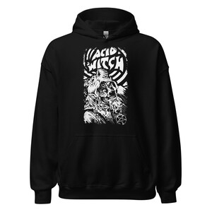 May include: Black hooded sweatshirt with a white graphic. The graphic features the text "ACID WITCH" above a detailed illustration of a creature with a pentagram. The design is in a bold, illustrative style.