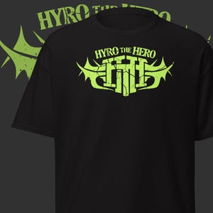 Könnte beinhalten: Schwarzes T-Shirt mit dem Text "HYRO THE HERO" in verblichener, neongrüner Schrift oben und einem passenden Logo in der Mitte. Das Logo zeigt die Worte "HYRO the HERO" in einer stilisierten Schriftart.