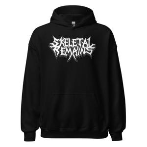 May include: Black hooded sweatshirt with the text "SKELETAL REMAINS" in a white, stylized font. The text has a shadow effect, adding depth to the design. The sweatshirt has a drawstring hood and a front pocket.