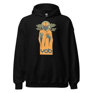 May include: Black hoodie featuring a graphic of a figure wearing headphones and an orange robe, with the letters "yob" in a teal font. The figure has a green halo and is flanked by stylized green trees.