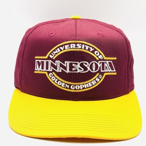 May include: A maroon and gold baseball cap with the text "UNIVERSITY OF MINNESOTA GOLDEN GOPHERS" in white and gold. The cap has a yellow brim and a yellow button on top.