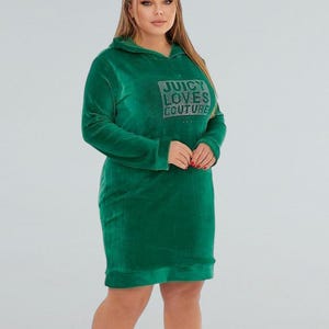 Könnte beinhalten: Ein grünes Kapuzenkleid mit langen Ärmeln. Das Kleid hat den Text "JUICY LOVES COUTURE" in Strasssteinen auf der Brust. Das Kleid ist aus einem weichen, samtartigen Material gefertigt.