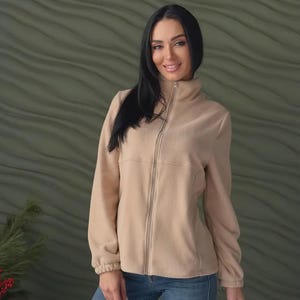 May include: A beige fleece jacket featuring a high collar, a full-length front zipper, and long sleeves with elasticized cuffs. The jacket is paired with blue denim jeans, creating a simple and functional outfit for cooler weather conditions.