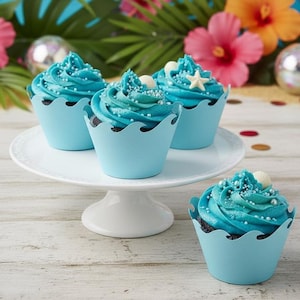 May include: Four cupcakes with blue frosting and decorative sprinkles sit on a white cake stand. The cupcakes are in light blue paper cups with a wave design. Tropical flowers and decorations are in the background.