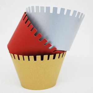May include: Three decorative paper cups in red, silver, and gold. Each cup has a unique notched edge design. The cups are stacked, with the red cup on top, silver in the middle, and gold on the bottom.