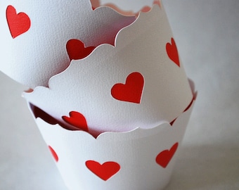 May include: White cupcake liners with scalloped edges and red heart cutouts. The liners are stacked, showcasing the heart design. Ideal for baking and adding a festive touch to treats.