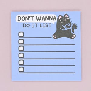 May include: A pale blue notepad featuring the text "DON'T WANNA DO IT LIST" in white. A black cat illustration is on the right. The notepad has six check boxes and horizontal lines for writing.