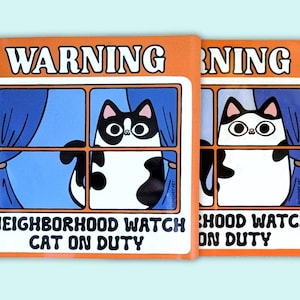 May include: Orange and white sign with the text "WARNING NEIGHBORHOOD WATCH CAT ON DUTY" and a cartoon black and white cat peeking out of a window.