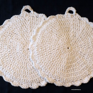 May include: Two white crocheted pot holders with scalloped edges and a loop handle.