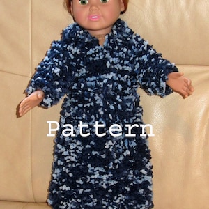 May include: A doll wearing a navy blue and white patterned robe, matching slippers, and a belt. The word "Pattern" is printed on the robe. The doll has red hair and green eyes.