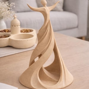 Könnte beinhalten: Eine hellfarbene Holzskulptur einer Figur mit ausgestreckten Armen. Das abstrakte Design weist fließende Linien und offene Räume auf, wodurch ein Gefühl der Bewegung entsteht. Die Skulptur steht auf einem hellen Holztisch.