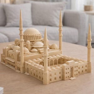 Könnte beinhalten: Ein detailliertes Holzmodell einer Moschee mit mehreren Kuppeln, Minaretten und gewölbten Eingängen. Das Modell ist aus hellem Holz gefertigt und steht auf einem hellen Holztisch. Der Hintergrund umfasst ein Sofa und eine dekorative Vase.