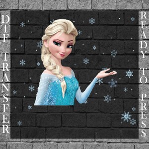 May include: A DTF (Direct to Film) transfer featuring a cartoon image of a blonde woman in a blue dress, surrounded by snowflakes. The words "READY TO PRESS" are printed vertically on the right side of the image. The background is a black brick wall.