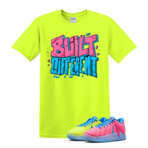 May include: A neon yellow t-shirt with the words "BUILT DIFFERENT" in pink and blue block letters. The shirt is paired with a pair of colorful sneakers, one yellow and blue, the other pink and blue.