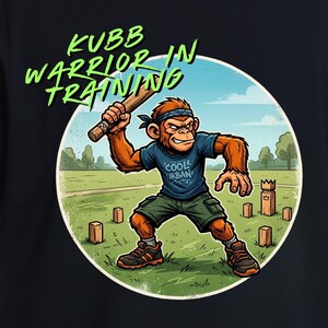 May include: A black t-shirt featuring a circular graphic on the back. The illustration depicts a cartoon monkey wearing a blue shirt, green shorts, and a bandana, holding a wooden baton. The text "KUBB WARRIOR IN TRAINING" is printed in green.