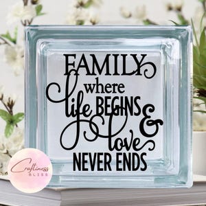 May include: A clear glass block with the text "FAMILY where life BEGINS & love NEVER ENDS" in black lettering.