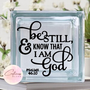 May include: A glass block with the words "Be still, and know that I am God" in black lettering. The words "Psalms 46:10" are also included in black lettering.