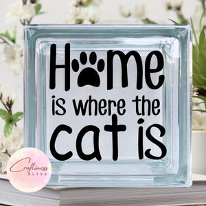 May include: A glass block with the text "Home is where the cat is" in black lettering. A paw print is included in the word "Home".