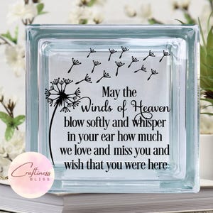 May include: A clear glass block with a dandelion design and the text "May the Winds of Heaven blow softly and whisper in your ear how much we love and miss you and wish that you were here."