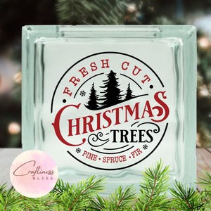 May include: A glass block with a red and black design that says "Fresh Cut Christmas Trees" with a pine, spruce, and fir graphic.