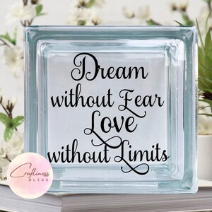 May include: A glass block with the text "Dream without Fear Love without Limits" in black lettering. The block is clear and has a frosted finish.