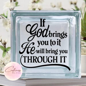 May include: A glass block with a black vinyl decal that reads "If God brings you to it He will bring you through it".